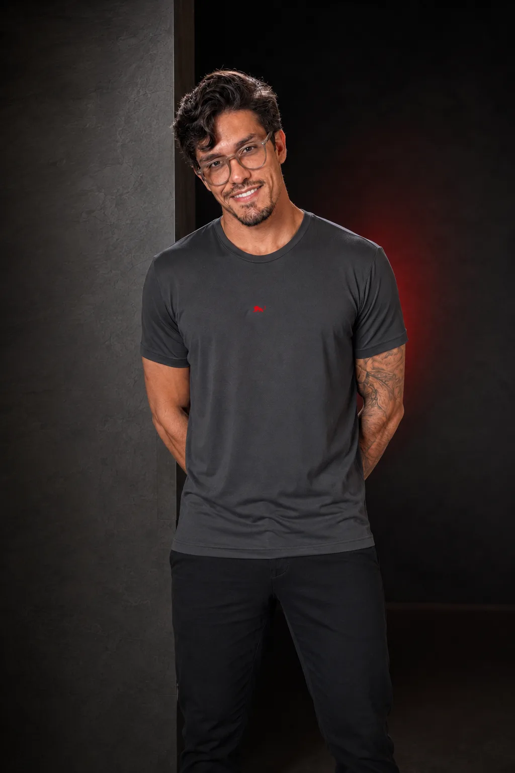 Modelo veste camiseta cinza chumbo da Lion Brazil com o leão bordado no peito, mãos para trás, ensaio de estúdio · infraestrutura Criateevidade da Lion Brazil