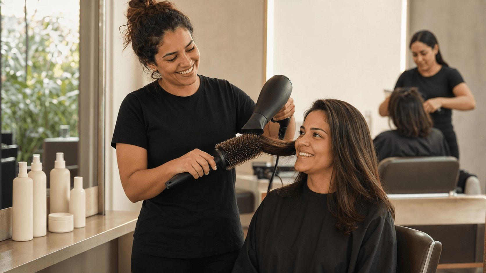 Cabeleireira de camiseta preta lisa finalizando a escova de uma cliente no salão