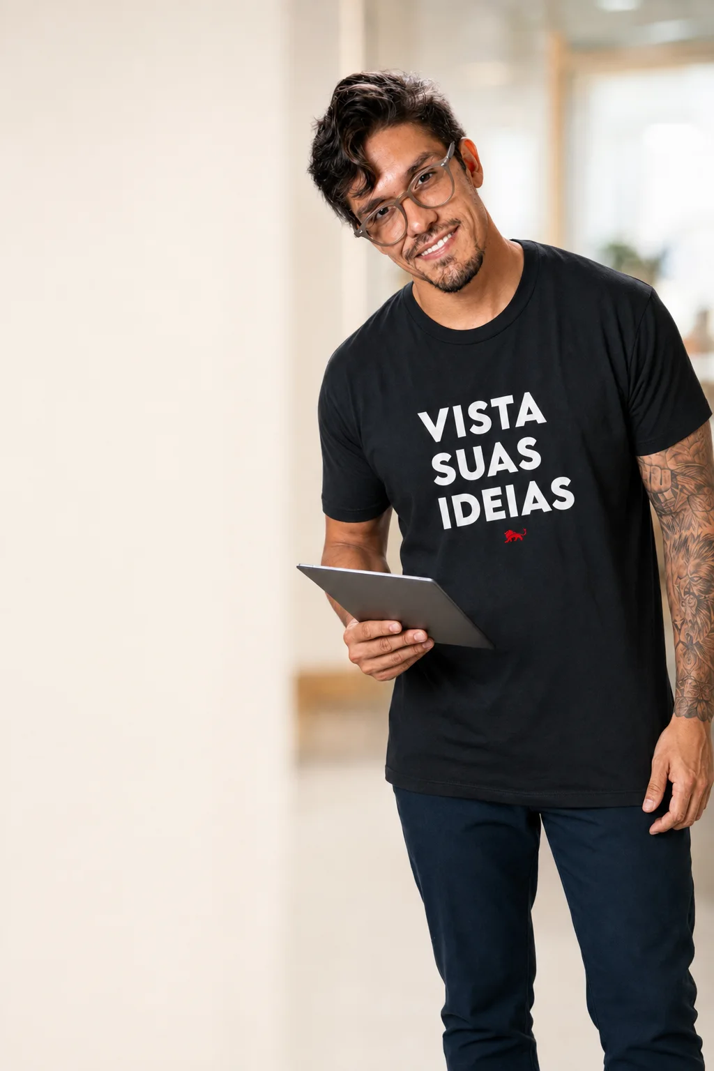 Homem sorrindo com um tablet na mão, vestindo camiseta preta da Lion Brazil com a estampa Vista suas ideias