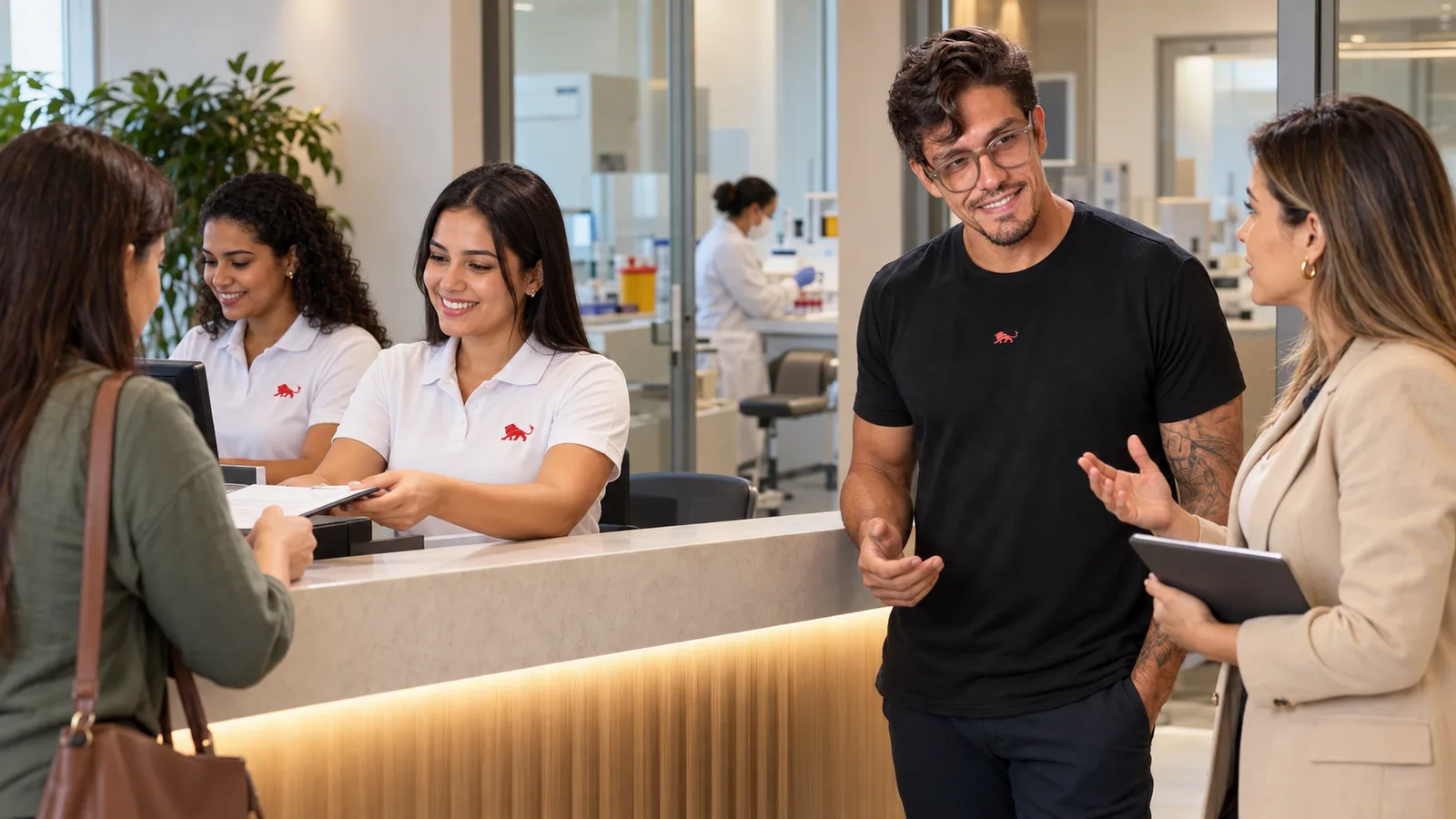 Atendentes de camisa polo branca com o leão da Lion recebem um paciente na recepção do laboratório, enquanto Pedro Costa conversa com a gerente.