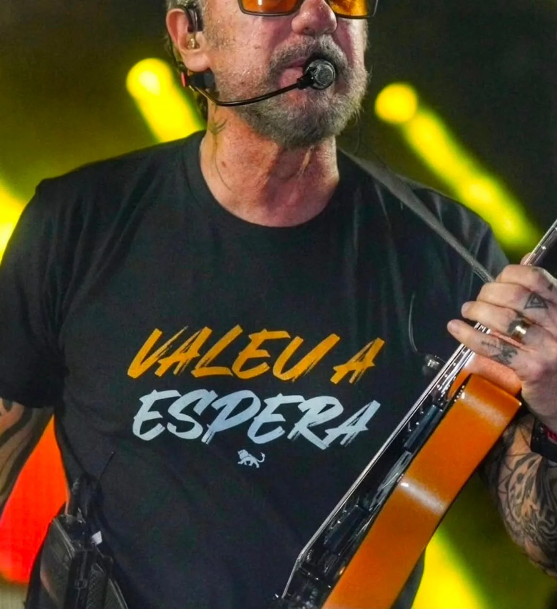 Tuca Fernandes cantando no palco com camiseta preta personalizada da Lion Brazil