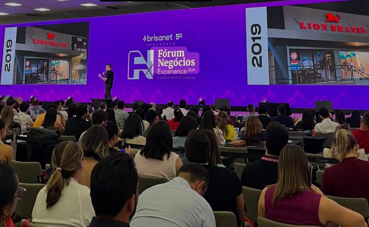 Palestra no Fórum Negócios Experience com a loja da Lion Brazil no telão diante da plateia