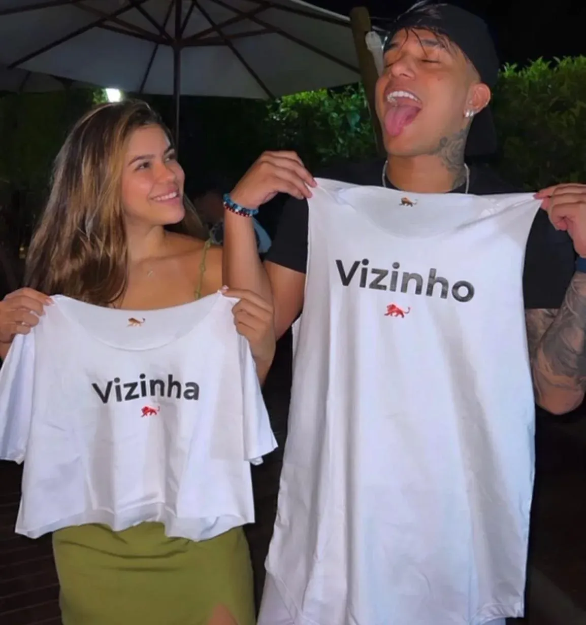 Casal segurando camisetas brancas Lion Brazil estampadas Vizinho e Vizinha